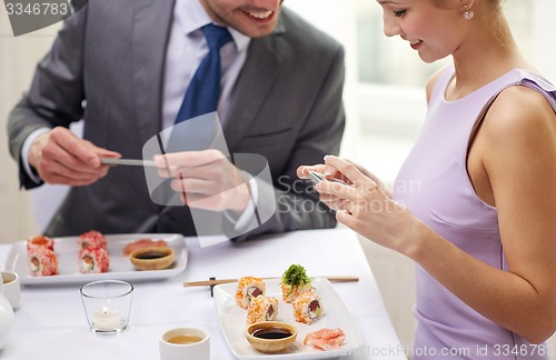 Image of close up of couple with smartphones at restaurant