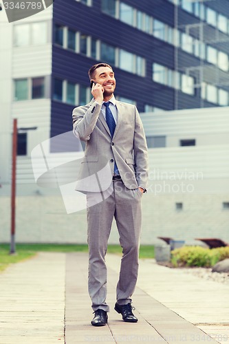 Image of smiling businessman with smartphone outdoors