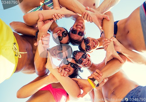 Image of smiling friends in circle on summer beach