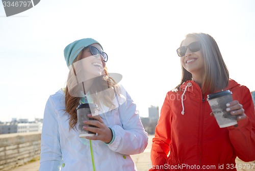 Image of happy teenage girls with coffee cups on street