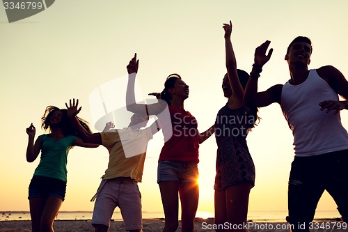 Image of smiling friends dancing on summer beach