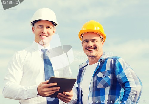 Image of smiling builders in hardhats with tablet pc