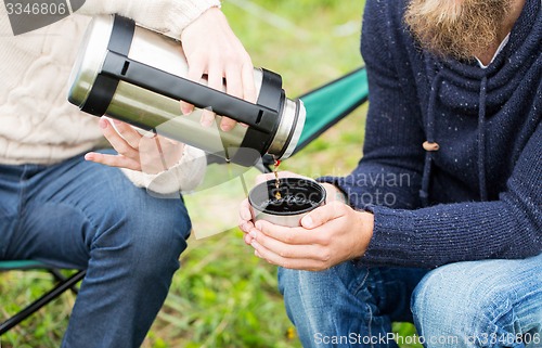 Image of close up of hikers pouring tea from thermos to cup