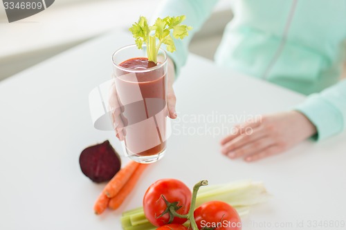 Image of close up of woman hands with juice and vegetables