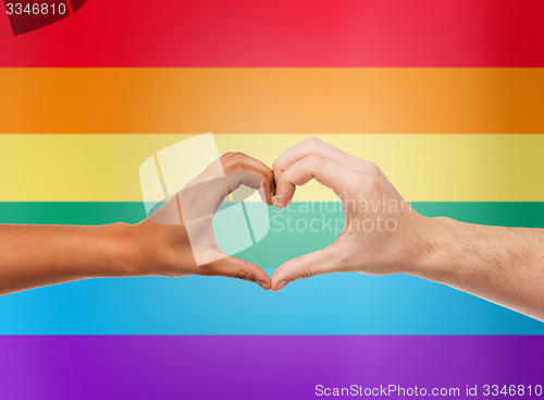 Image of human hands showing heart shape over rainbow