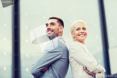 Image of smiling businessmen standing over office building