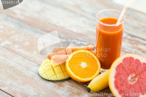 Image of close up of fresh juice glass and fruits on table