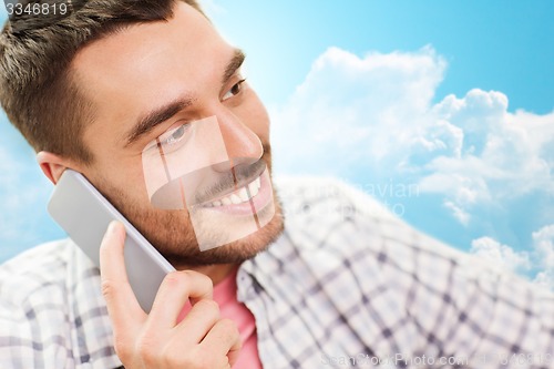 Image of smiling young man calling on smartphone