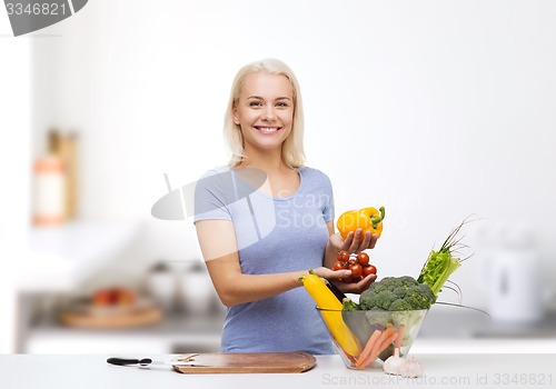 Image of smiling young woman cooking vegetables in kitchen 