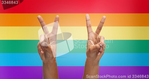 Image of hands showing peace sign over rainbow stripes