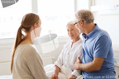 Image of happy family visiting senior woman at hospital