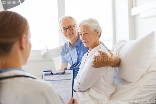 Image of senior woman and doctor with clipboard at hospital