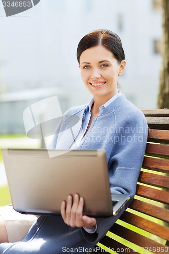 Image of smiling business woman with laptop in city