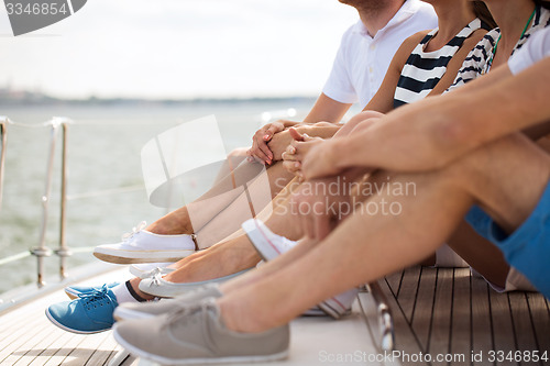 Image of close up of friends legs sitting on yacht deck