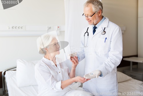 Image of doctor giving medicine to senior woman at hospital