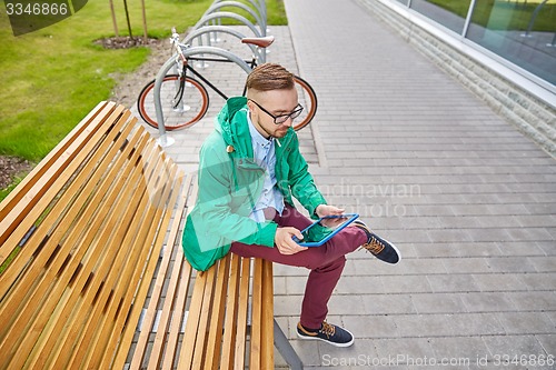 Image of happy young hipster man with tablet pc and bike