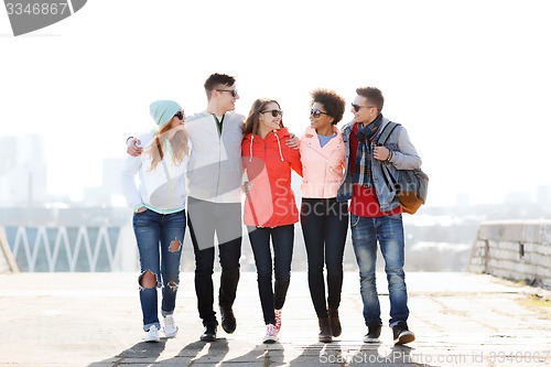 Image of happy teenage friends walking along city street