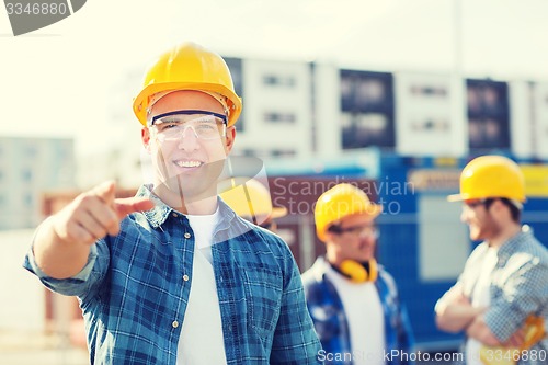 Image of group of smiling builders in hardhats outdoors