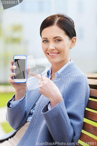 Image of young smiling businesswoman showing smartphone