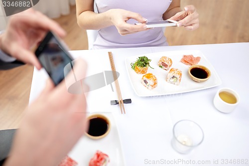 Image of close up of couple with smartphones at restaurant