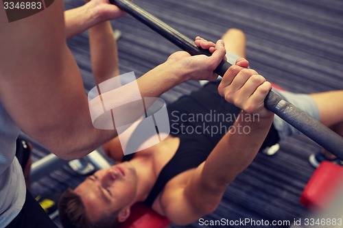 Image of two young men with barbell flexing muscles in gym