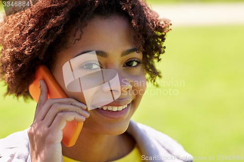 Image of happy african woman calling on smartphone outdoors