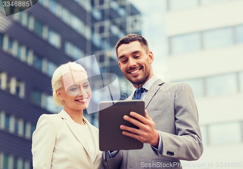 Image of smiling businessmen with tablet pc outdoors