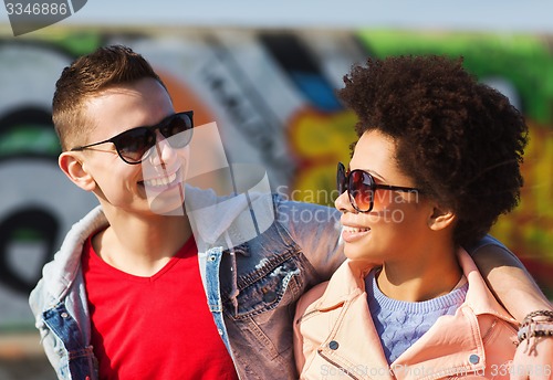 Image of happy teenage friends in shades hugging outdoors