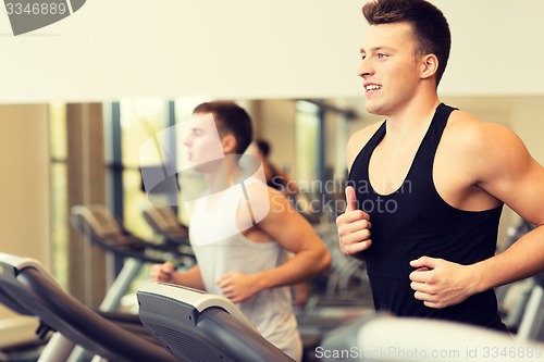 Image of smiling men exercising on treadmill in gym