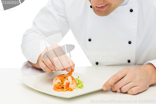 Image of close up of happy male chef cook decorating dish