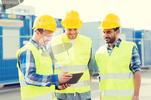 Image of smiling builders in hardhats with tablet pc