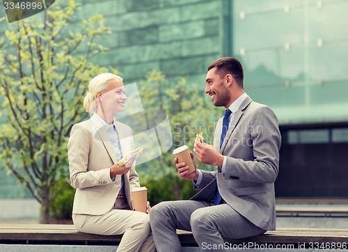 Image of smiling businessmen with paper cups outdoors