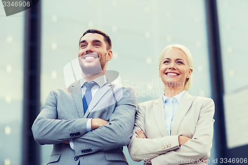 Image of smiling businessmen standing over office building