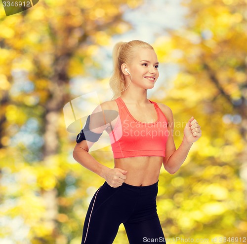 Image of sporty woman running with smartphone and earphones