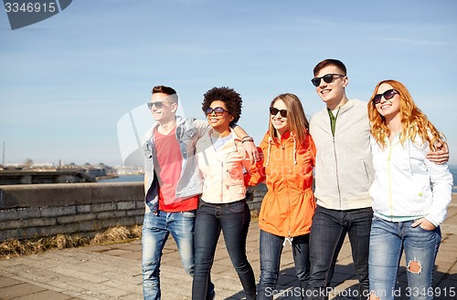 Image of happy teenage friends walking along city street