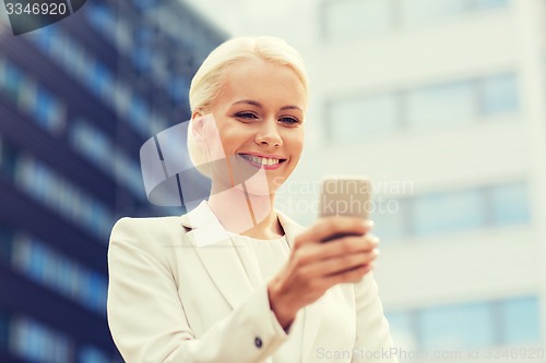 Image of smiling businesswoman with smartphone outdoors