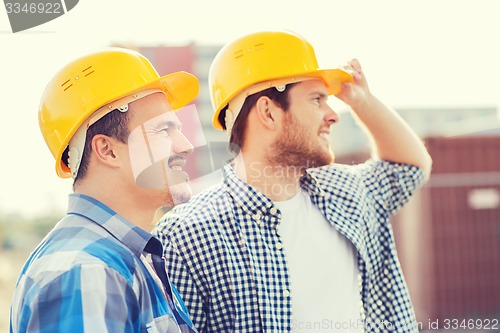 Image of group of smiling builders in hardhats outdoors