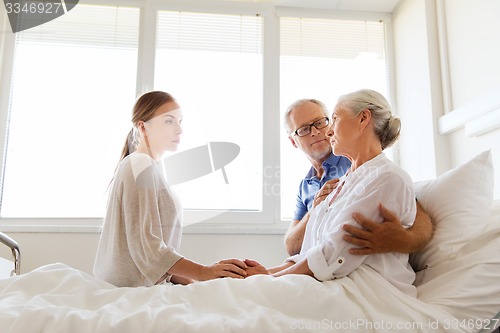 Image of family visiting ill senior woman at hospital