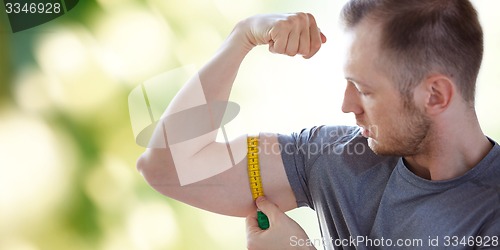 Image of close up of male hands with tape measuring bicep