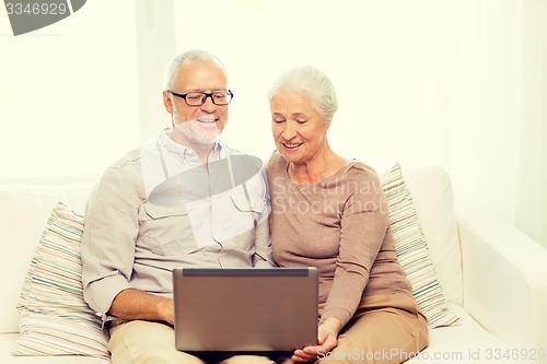 Image of happy senior couple with laptop at home