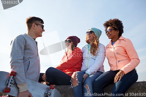 Image of happy teenage friends with skateboard on street