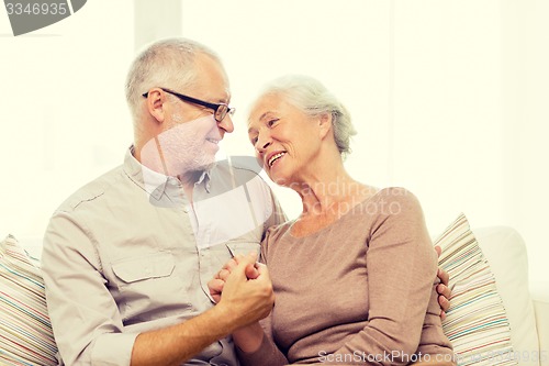 Image of happy senior couple hugging on sofa at home