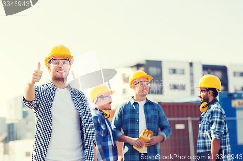 Image of group of smiling builders in hardhats outdoors