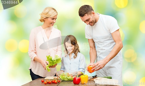 Image of happy family cooking vegetable salad for dinner