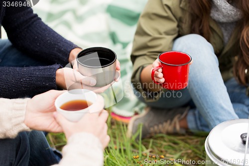 Image of close up of hikers drinking tea from cups at camp