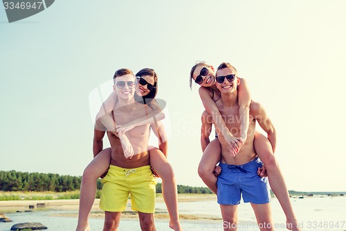 Image of smiling friends in sunglasses on summer beach