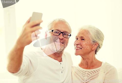Image of happy senior couple with smartphone at home