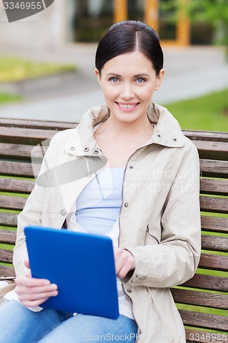 Image of woman with tablet pc sitting on bench in park