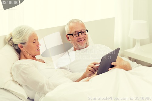 Image of happy senior couple with tablet pc at home