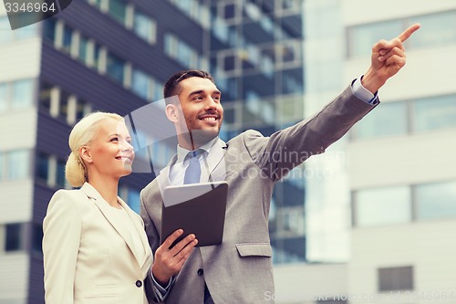 Image of smiling businessmen with tablet pc outdoors